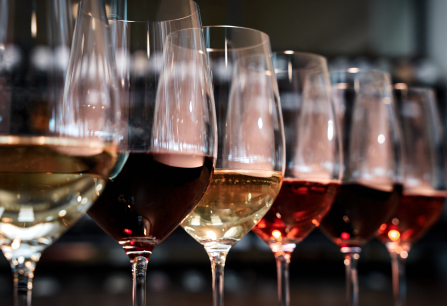 Reihe von Weingläsern mit verschiedenfarbigen Weinen in elegantem Ambiente.