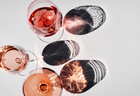 Rosé-Weingläser, von oben fotografiert, werfen kunstvolle Schatten auf weiße Oberfläche.