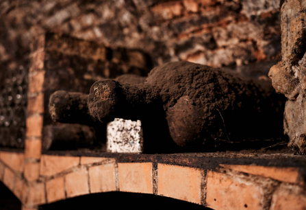 Verstaubte alte Weinflasche in einem ziegelsteinernen Weinkeller.
