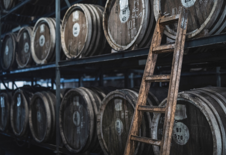 Holzfässer mit Leiter in einem dunklen Lagerraum.