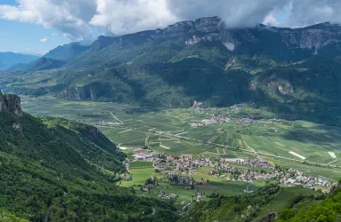 Panorama mit grüner Landschaft, Bergen, Feldern und einem Dorf im Tal.