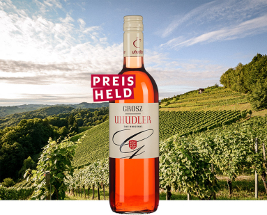 Roséweinflasche vor malerischer Weinberglandschaft unter klarem Himmel.