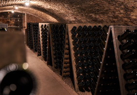 Gewölbekeller mit Holzregalen voller horizontal gelagerter Flaschen.
