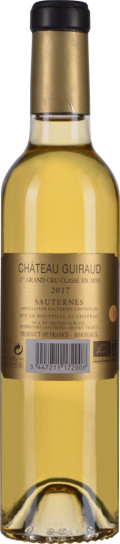 Goldgelber Wein in schlanker Flasche mit schwarzem Verschluss.