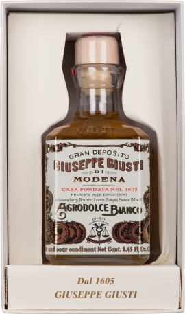 Transparente Glasflasche mit hellem Verschluss und dekorativem, nostalgischem Etikett in Geschenkbox.