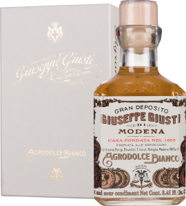 Hellbraune Flasche mit edlem Etikett vor passender Geschenkverpackung.