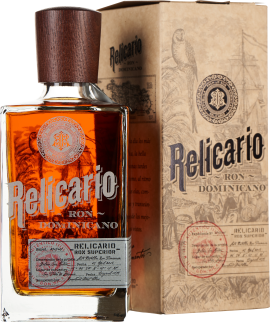 Klare, eckige Flasche mit dunkelbraunem Holzverschluss, gefüllt mit bernsteinfarbenem Getränk; im Hintergrund eine kunstvoll gestaltete, beige Verpackung mit Vintage-Grafiken.