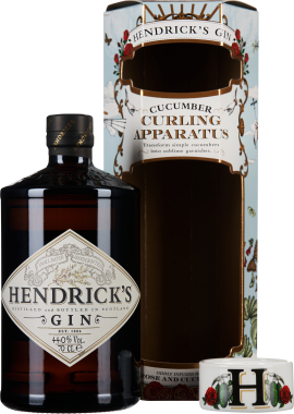 Braune Gin-Flasche mit großer, detailreicher Etikettierung, daneben eine dekorative Geschenkverpackung mit floralen und verspielten Elementen sowie ein Deckel mit der Initiale "H" und Rosenmotiven.