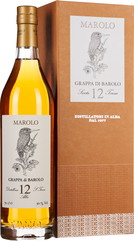 Eine elegante, goldfarbene Flasche Grappa mit edlem Etikett, das einen Vogel auf einem Ast zeigt. Die Flasche steht neben einer dazu passenden, stilvollen Verpackung in warmem Braunton mit feiner Textur und dezentem Muster.