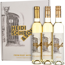 Ein Set aus drei Weinflaschen mit goldenen Verschlüssen vor einer weißen Geschenkbox. Die Flaschen und die Box sind mit einer eleganten Zeichnung einer Holztür verziert.