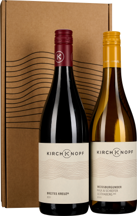 Zwei Weinflaschen mit elegantem Etikettendesign stehen vor einem schlichten, naturbraunen Geschenkkarton mit wellenförmiger Grafik. Die linke Flasche hat einen roten Schraubverschluss, die rechte einen gelben.