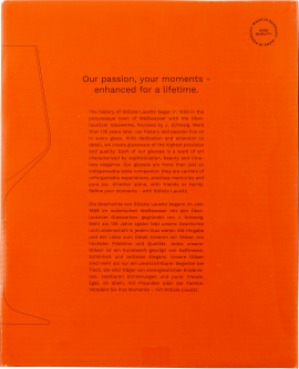 Orange Verpackung mit stilisierter Glaszeichnung und englisch-deutschem Text zur Markenphilosophie.