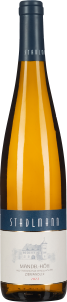 Eine Weinflasche mit einem blauen Hals und Etikett, goldgelber Wein schimmert durch das klare Glas. Darunter ein weißes Etikett mit einem grauen Gebäude und roten Akzenten.