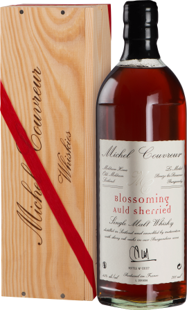 Eine elegante Flasche Whisky mit tiefem Bernsteinton, präsentiert in einer edlen Holzkiste mit rotem Band.