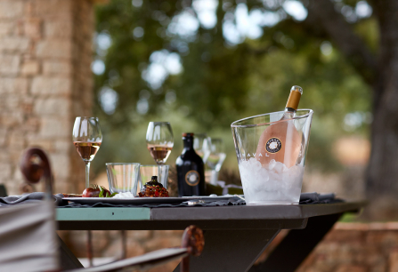 Gedeckter Tisch im Freien mit Weingläsern und einer Flasche im Eiskübel.
