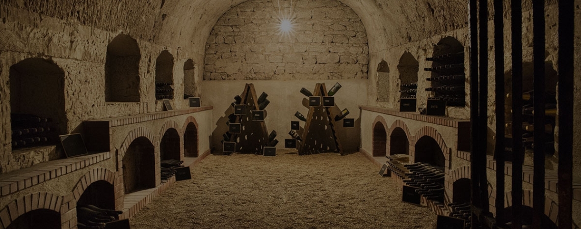 Historischer Weinkeller mit gewölbter Decke und Weinflaschen in Regalen.