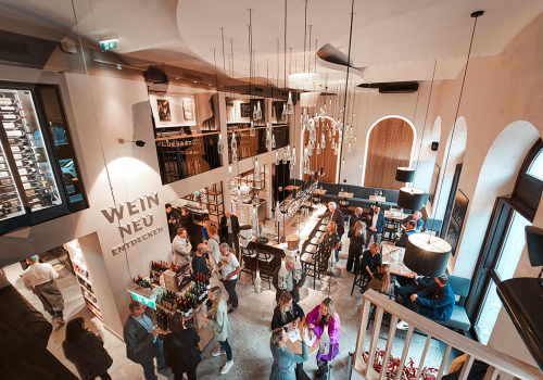 Elegante Weinbar mit hohen Decken, stilvollen Lampen und geselligem Ambiente.