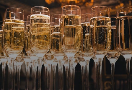 Viele gefüllte Sektgläser mit sprudelndem, goldenem Aperitif in einem eleganten Ambiente.
