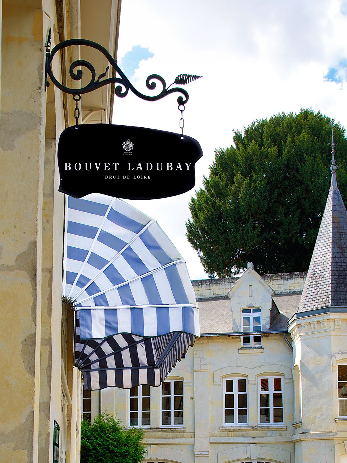 Elegantes schwarzes Metallschild mit gestreifter Markise vor historischem Gebäude.