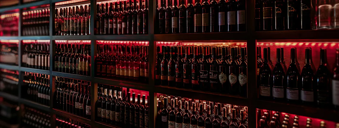 Regale voller Weinflaschen, stimmungsvoll beleuchtet mit warmem, rotem Licht.